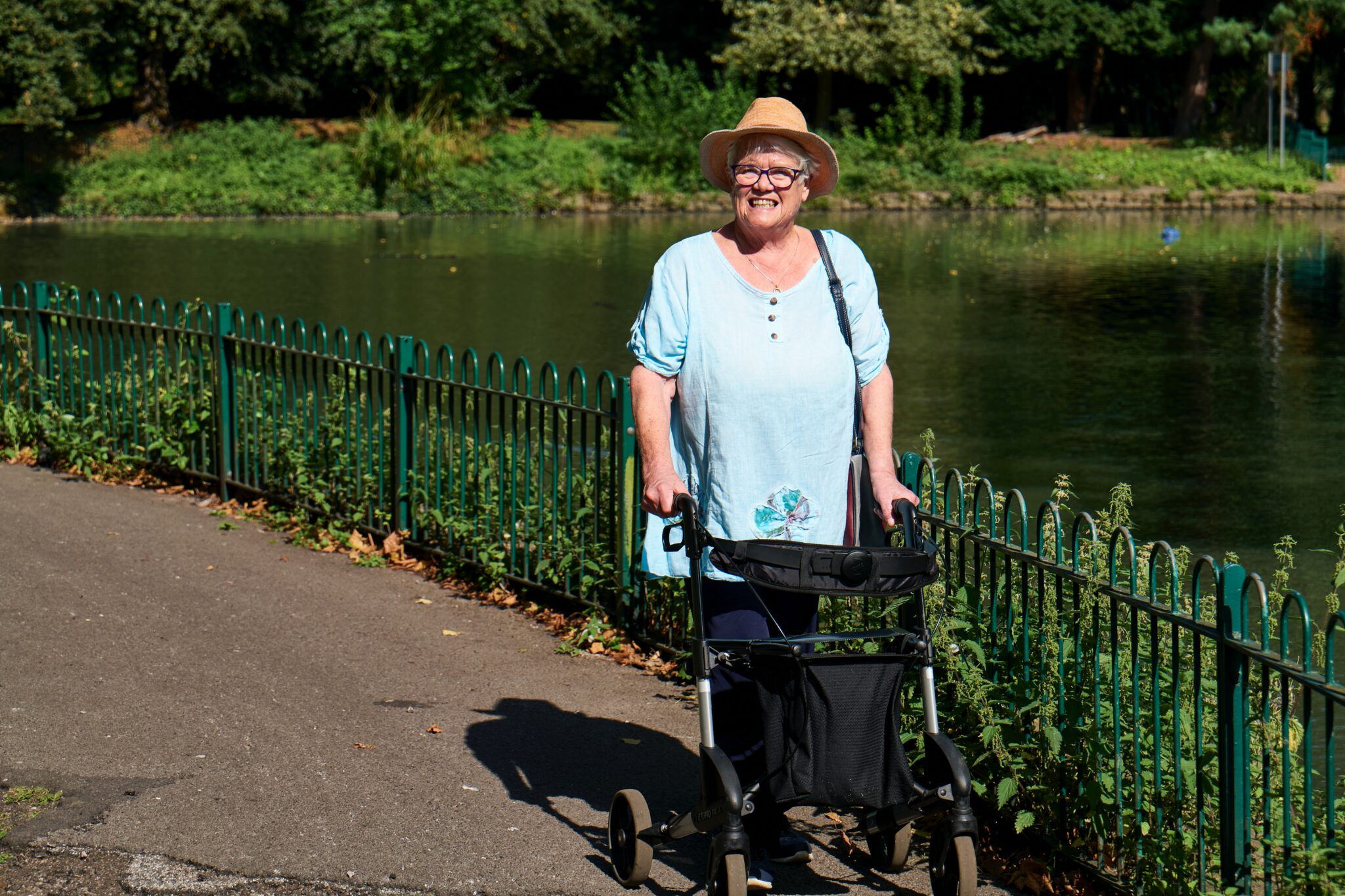 Lifestyle image of a woman in a park using a rollator to help her walk