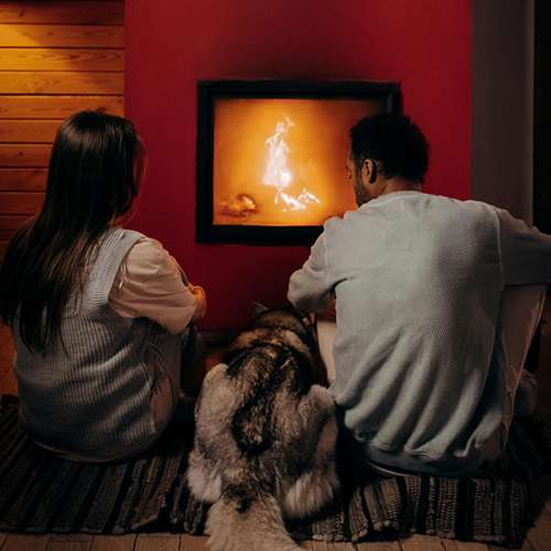 couple and dog sitting in front of stove