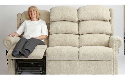Elderly woman sat on a triple reclining sofa.