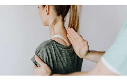 Close up of a womans back with a healthcare professional's hand.