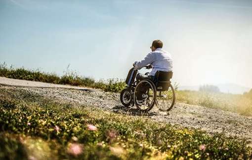 Man riding in a wheelchair while outdoors in a field