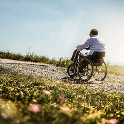 Man riding in a wheelchair while outdoors in a field