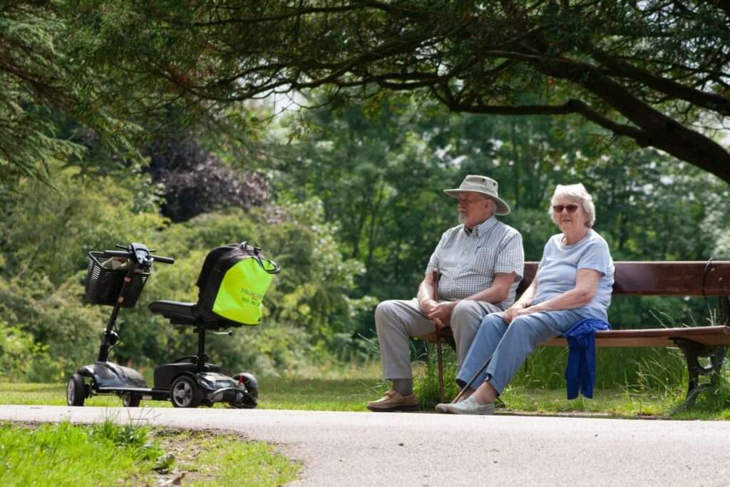 man and woman on bench next to mobility scooter