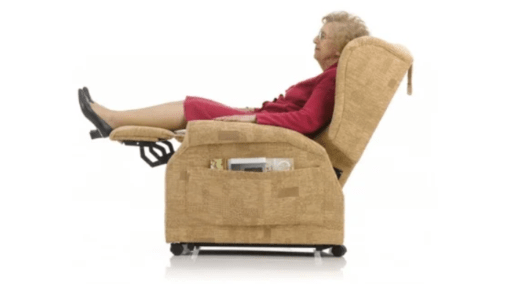 Elderly woman sat on a recliner rise and recline chair with her feet up. On a white background.