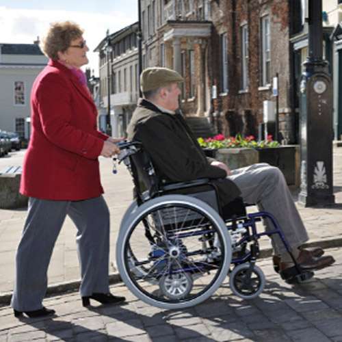 lady pushing man in wheelchair