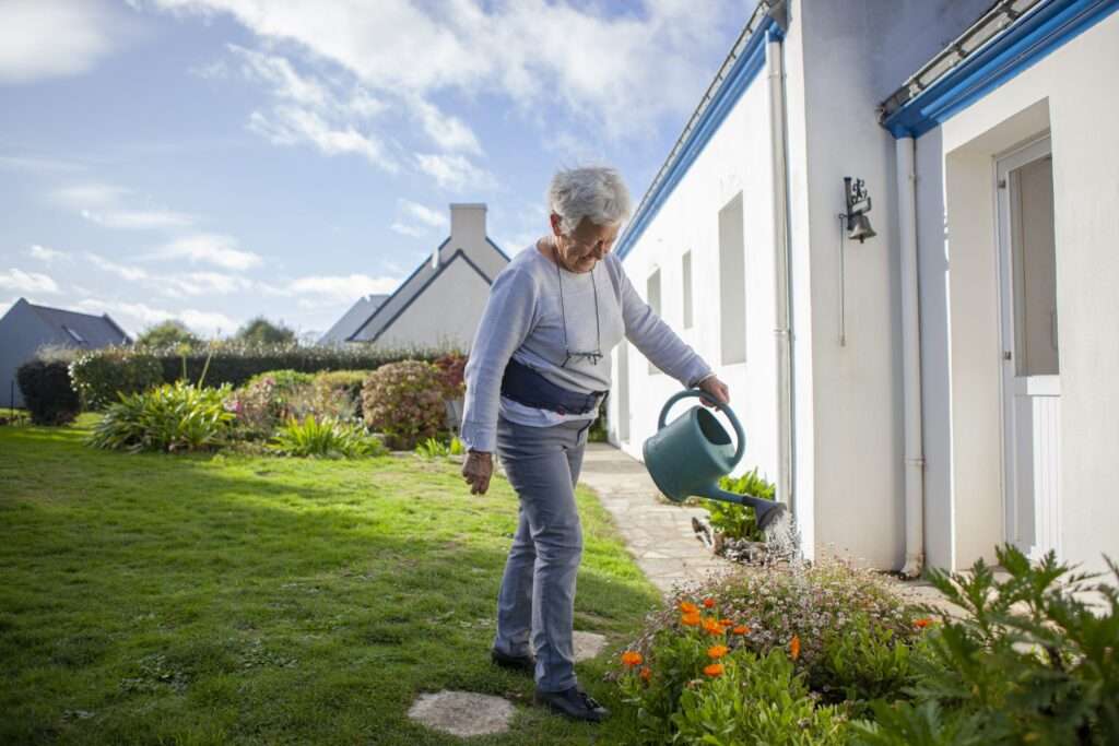 Woman watering her garden while wearing the HipGuard fracture protection belt.