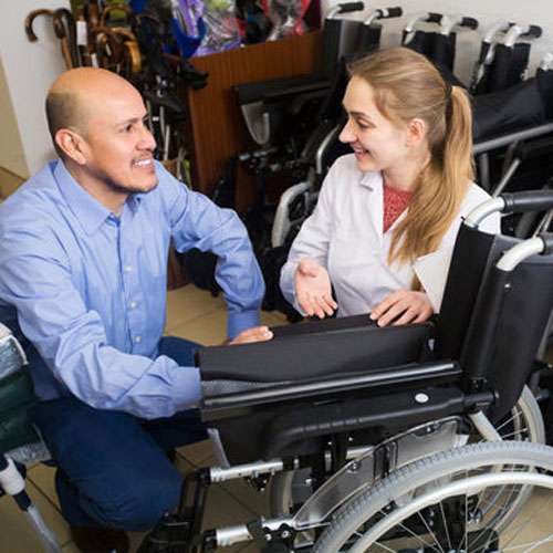 Male salesman advising a woman shopping for a folding, lightweight wheelchair.