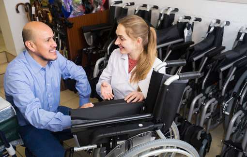 Male salesman advising a woman shopping for a folding, lightweight wheelchair.