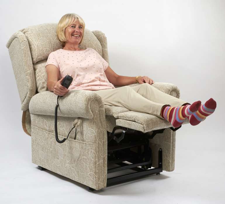 An elderly woman sitting on the Brecon electric orthopaedic riser recliner armchair with her legs extended on the footrest.