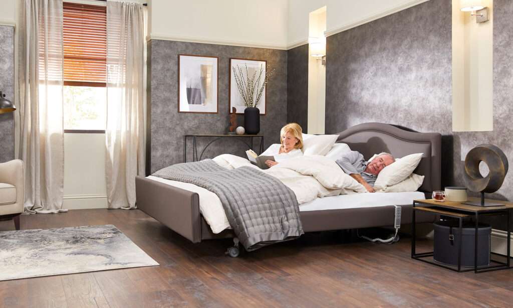 Lifestyle shot of an elderly couple in a bedroom sleeping on an adjustable double mobility recliner bed.