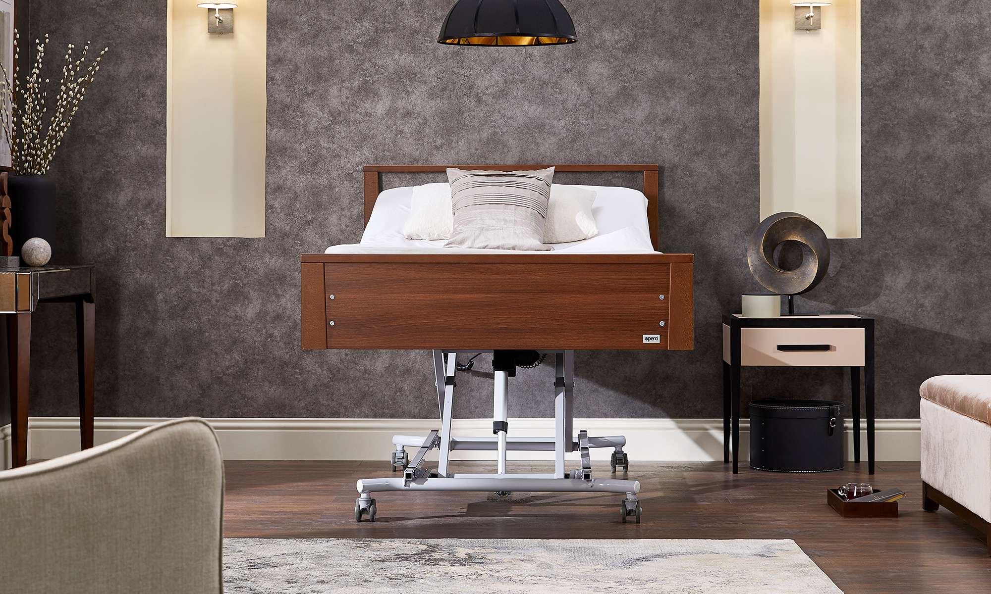 Lifestyle shot of the Opera Signature low footboard electric profiling recliner bed for patient care raised high and flat in a carpeted bedroom.