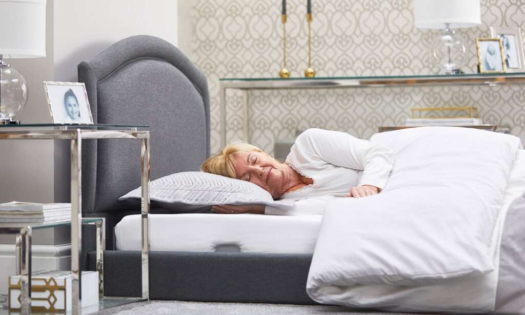 Solo comfort profiling mobility recliner bed. Close up of an elderly woman's head lying near the fabric headboard.