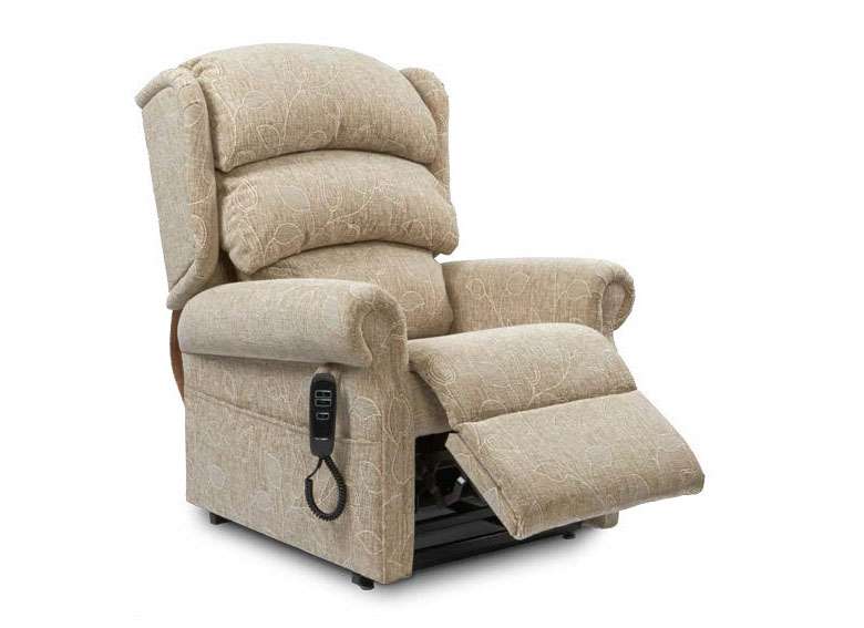 Product shot of a riser recliner armchair upholstered in beige fabric with a waterfall cushion backrest and a cushioned foortest partly out stretched.