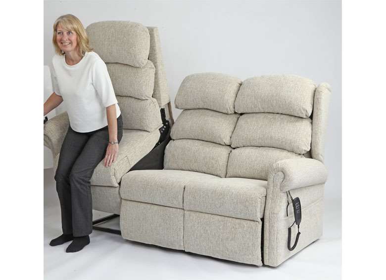 Product shot of an elderly woman using the rising function on a riser recliner lift chair sofa.
