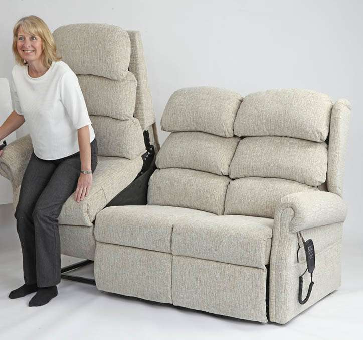 Elderly lady using the lift up feature on a orthopaedic riser recliner sofa.