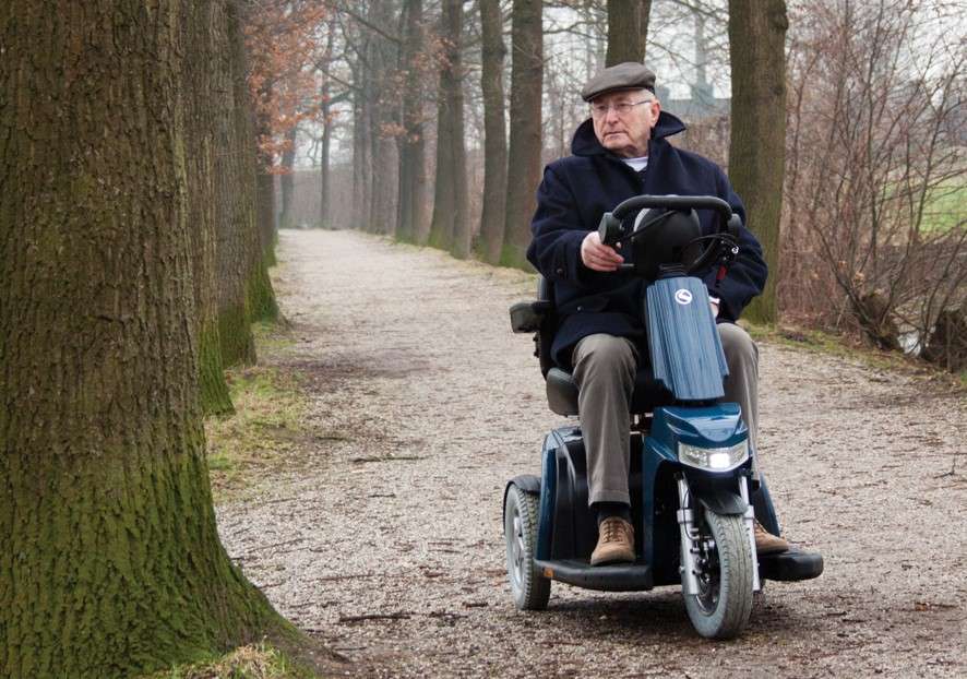 A man driving a mobility scooter through the woods.