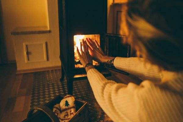 Someone warming their hands in front of an open fire.