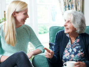 Elderly woman and younger woman in a care home looking at each other.