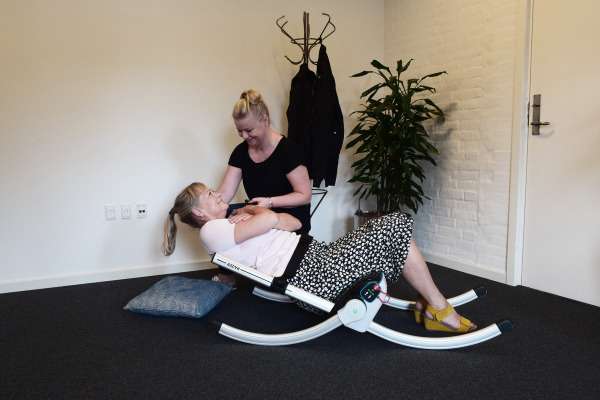 Woman being picked up from the floor with the Raizer 2 emergency lifting chair. The falls assistant is another woman and they are both indoors.