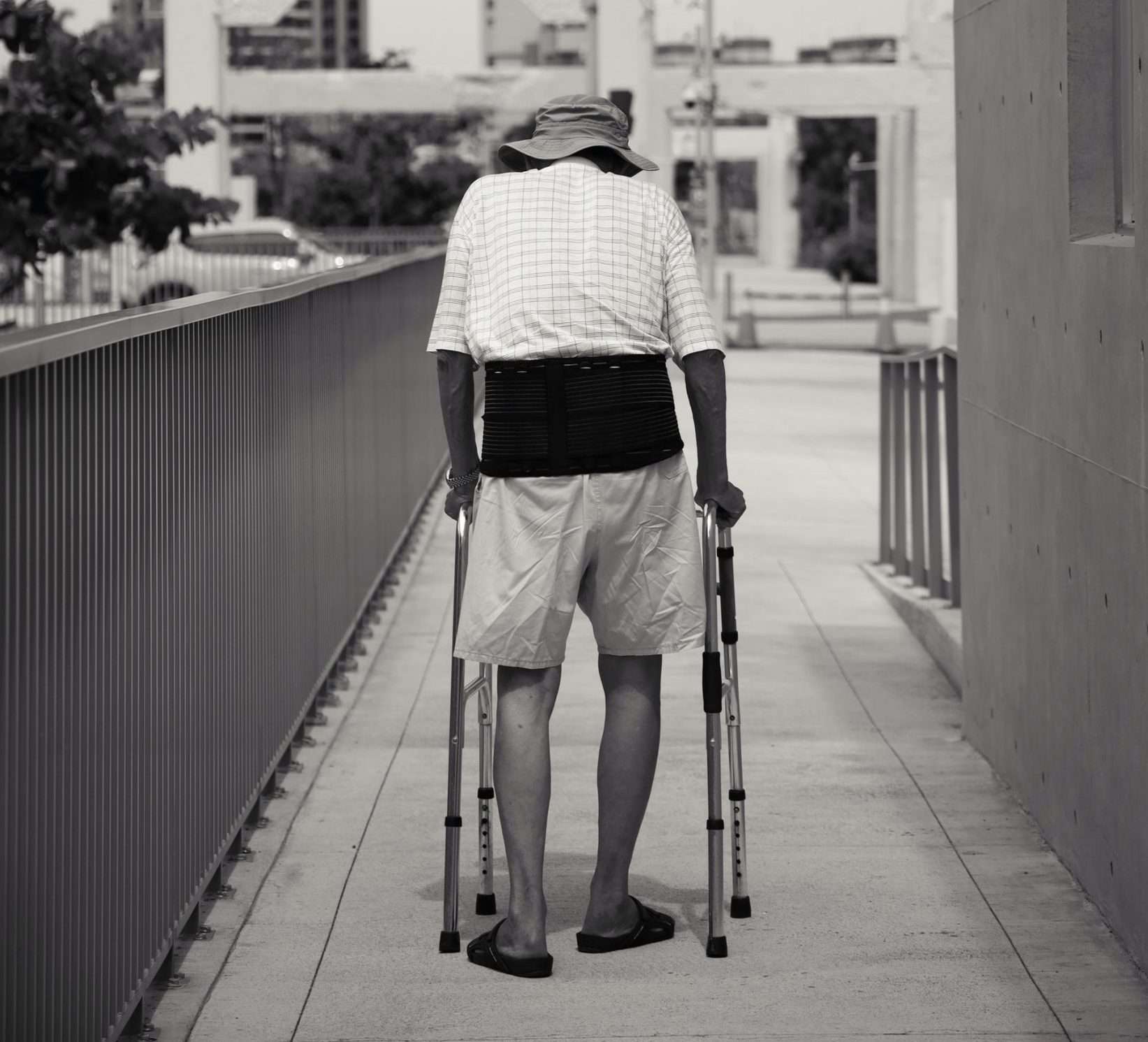 An elderly man walking alway using a walking frame.