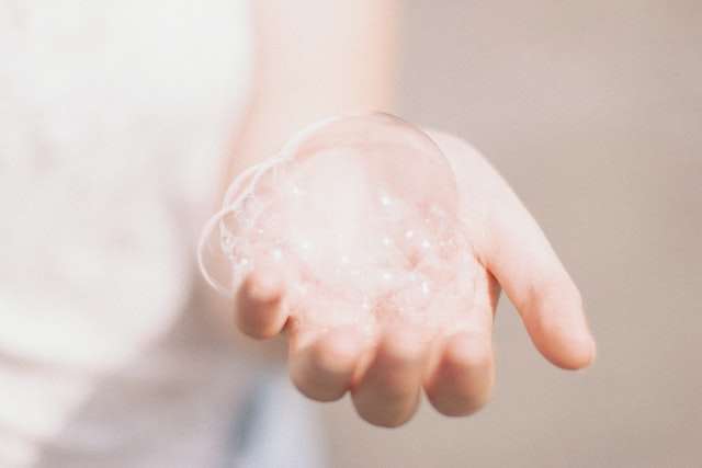 A hand cupping soapy bubbles.