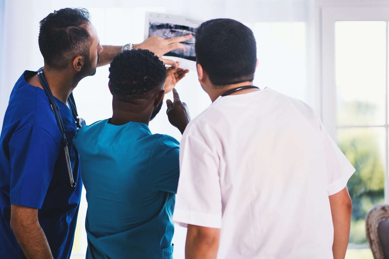 Three doctors stood examining an x-ray.