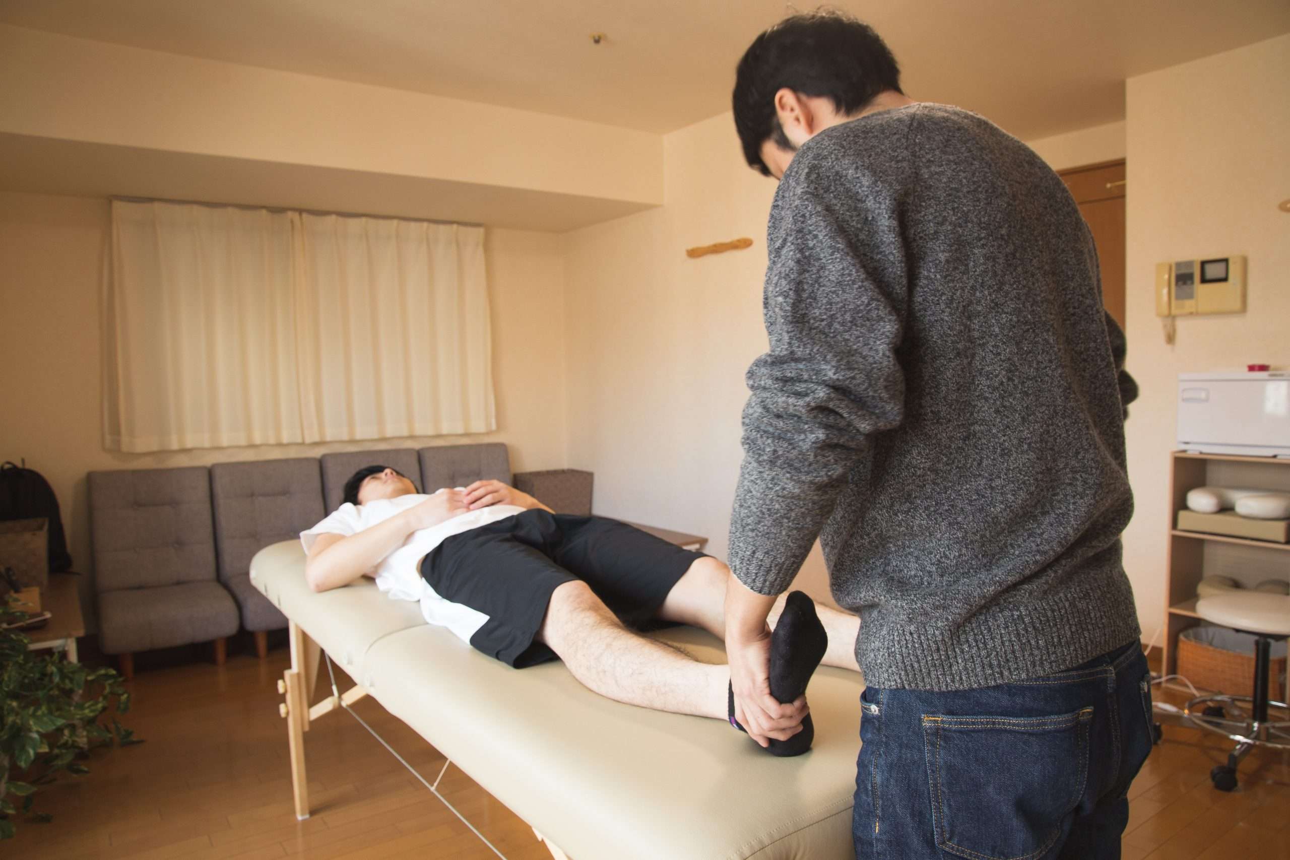 A person laid on a table with a physiotherapist examining them.