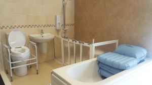 An accessible bathroom with grab rails and a shower chair.