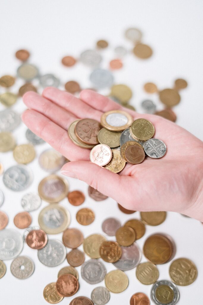 A human han holding some coins. More coins are on the table in the background.