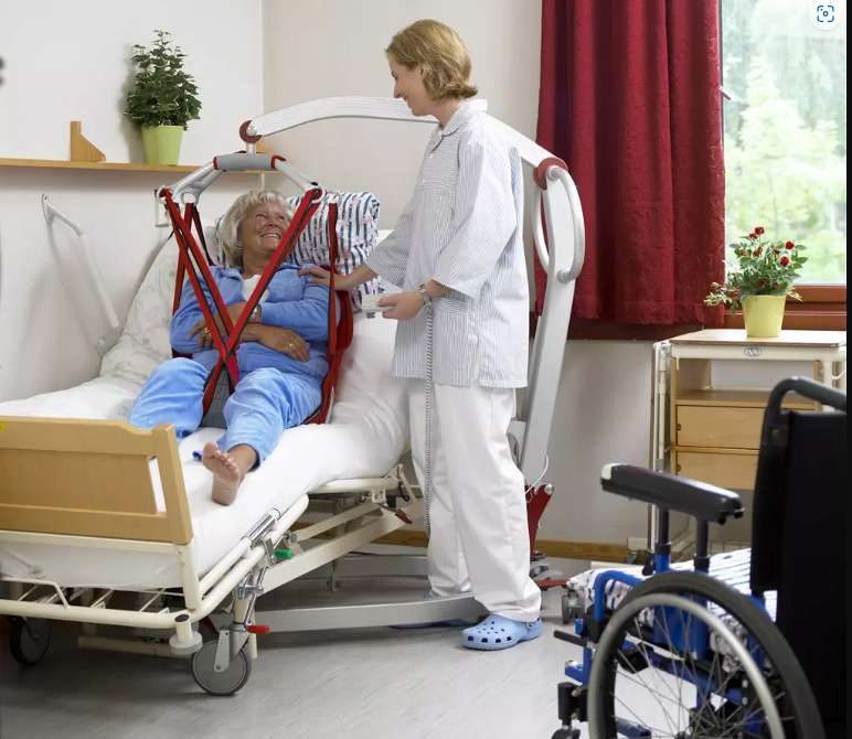 Nurse using the Smart 150 patient lift hoist equipment to transfer an elderly woman from her bed.