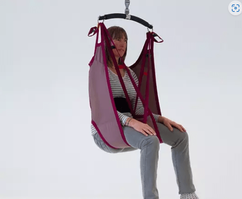 Product shot of a woman being lifted using a rigid lowback sling. The sling is red and the woman is wearing grey jeans.