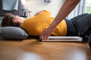 Shows a patient lying on their back, with a Raizer backrest being slid into position