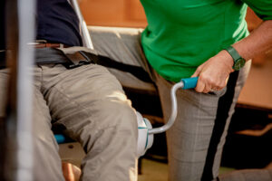 A carer winding the crank handle on a Raizer M to bring the fallen person to a seated position