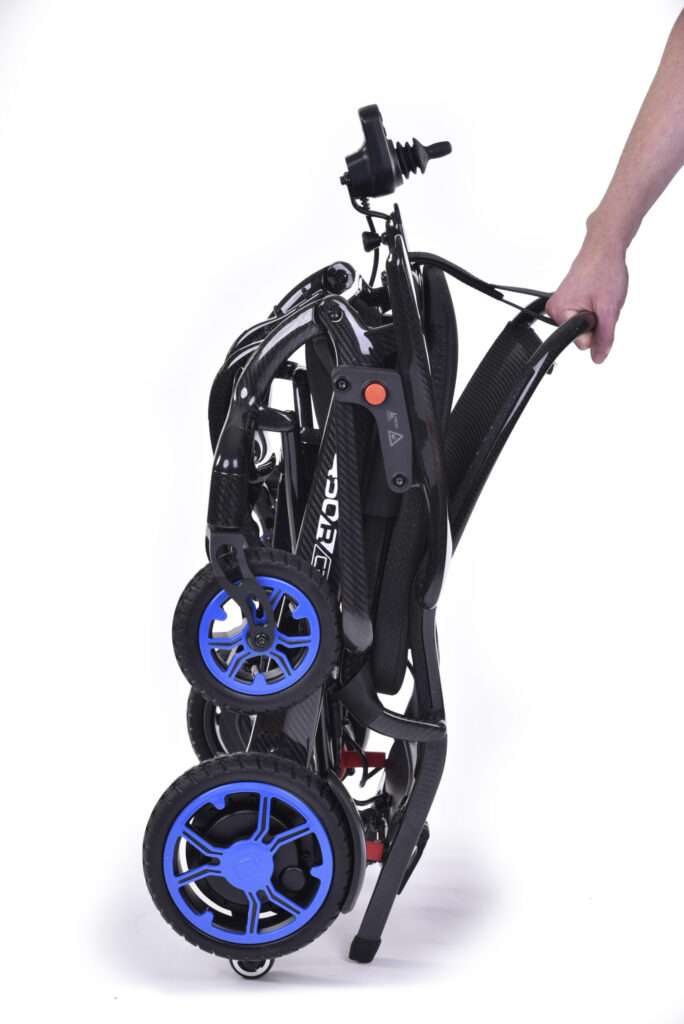 Product shot of the Quickie q50r lightweight carbon fibre foldable compact wheelchair folded down, being carried by the hand of a person.