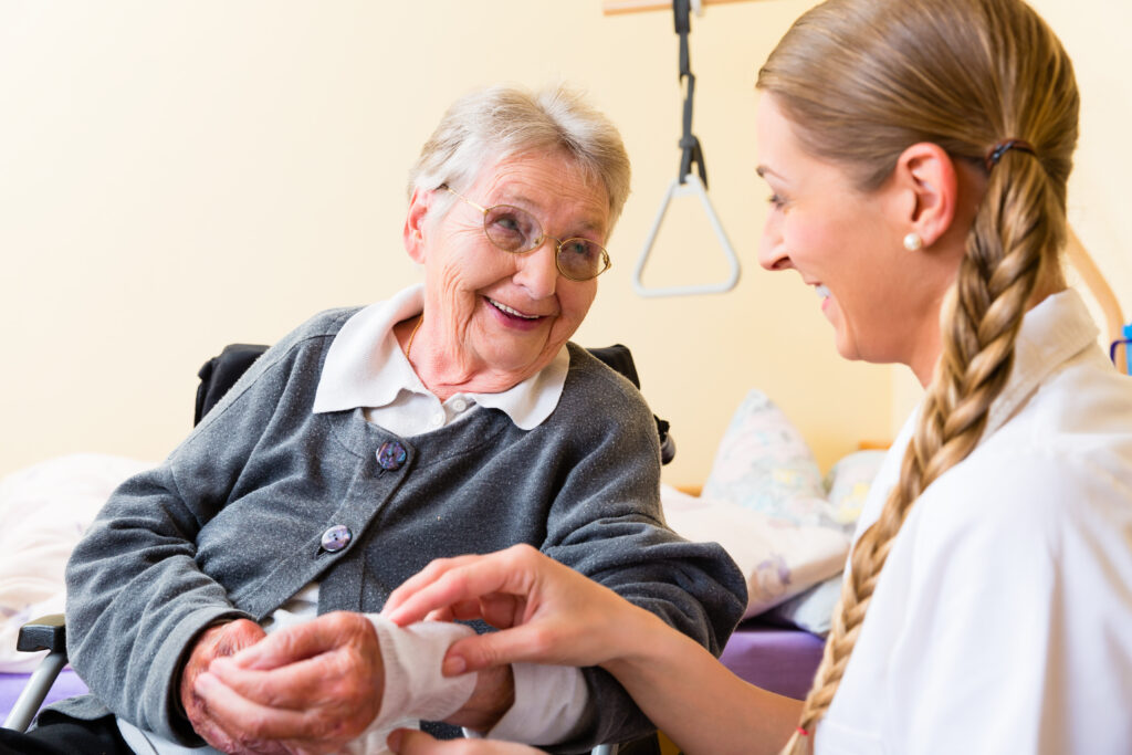 Nurse taking care of senior woman in retirement home bandaging a wound - pressure care