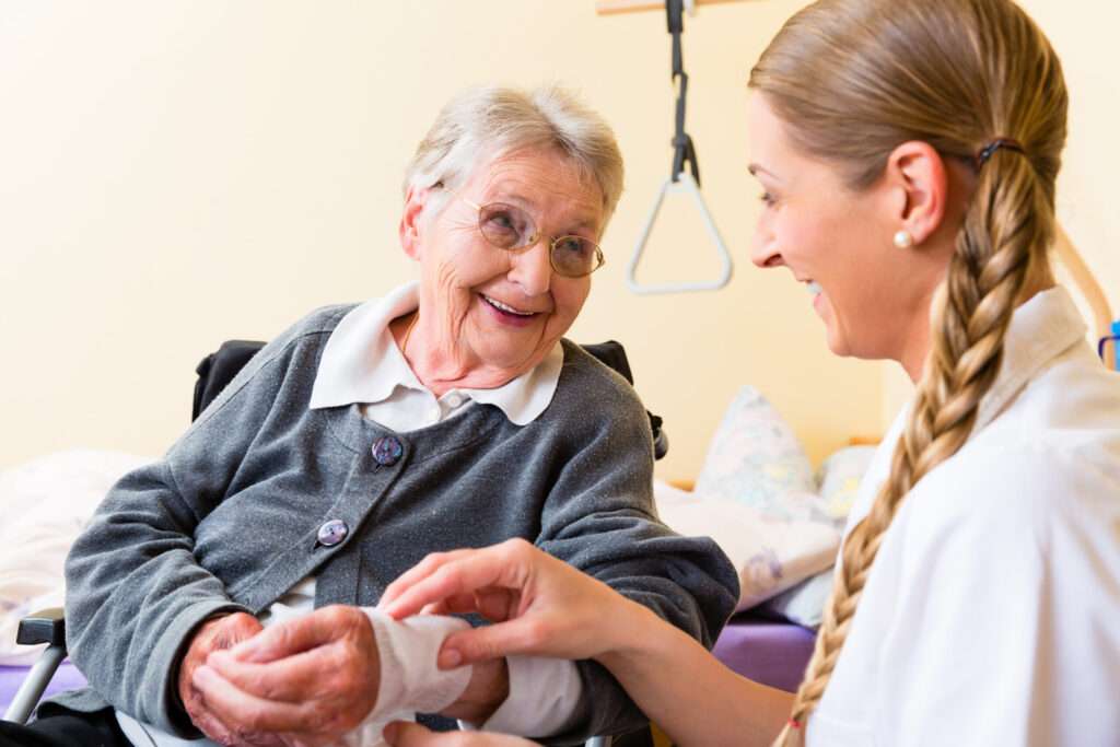 Nurse taking care of senior woman in retirement home bandaging a wound - pressure care