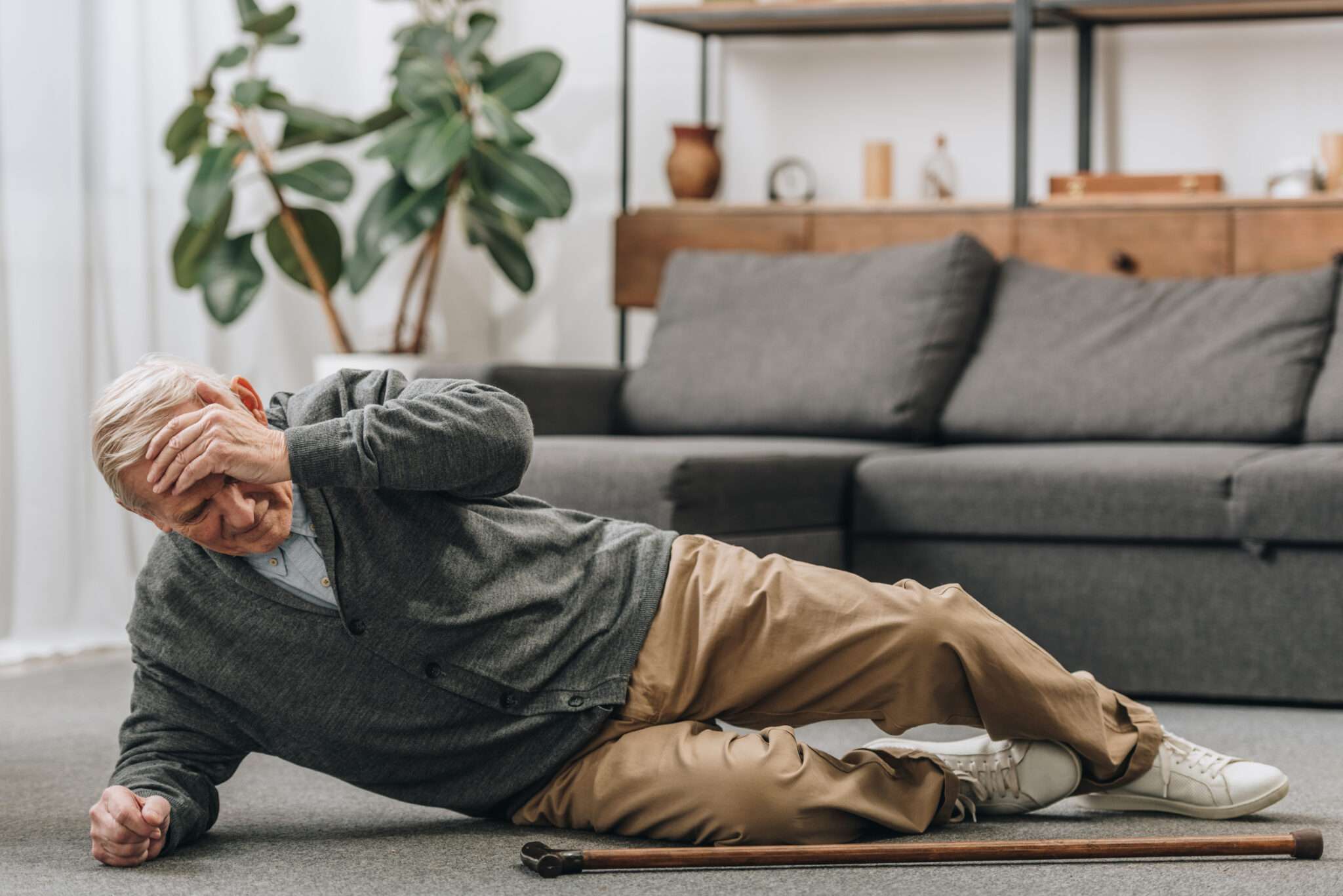 old man fallen on the floor touching forehead