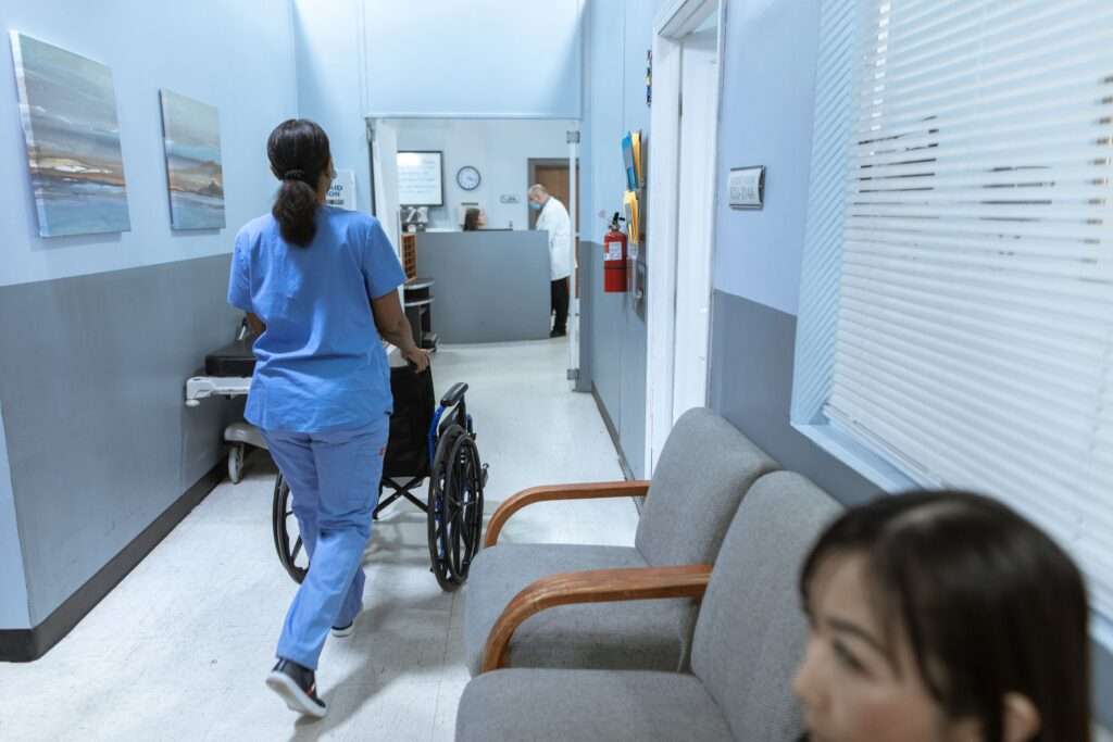 nurse transporting wheelchair down hospital corridor